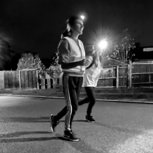 Female runners wear headtorches and pair up for a night run